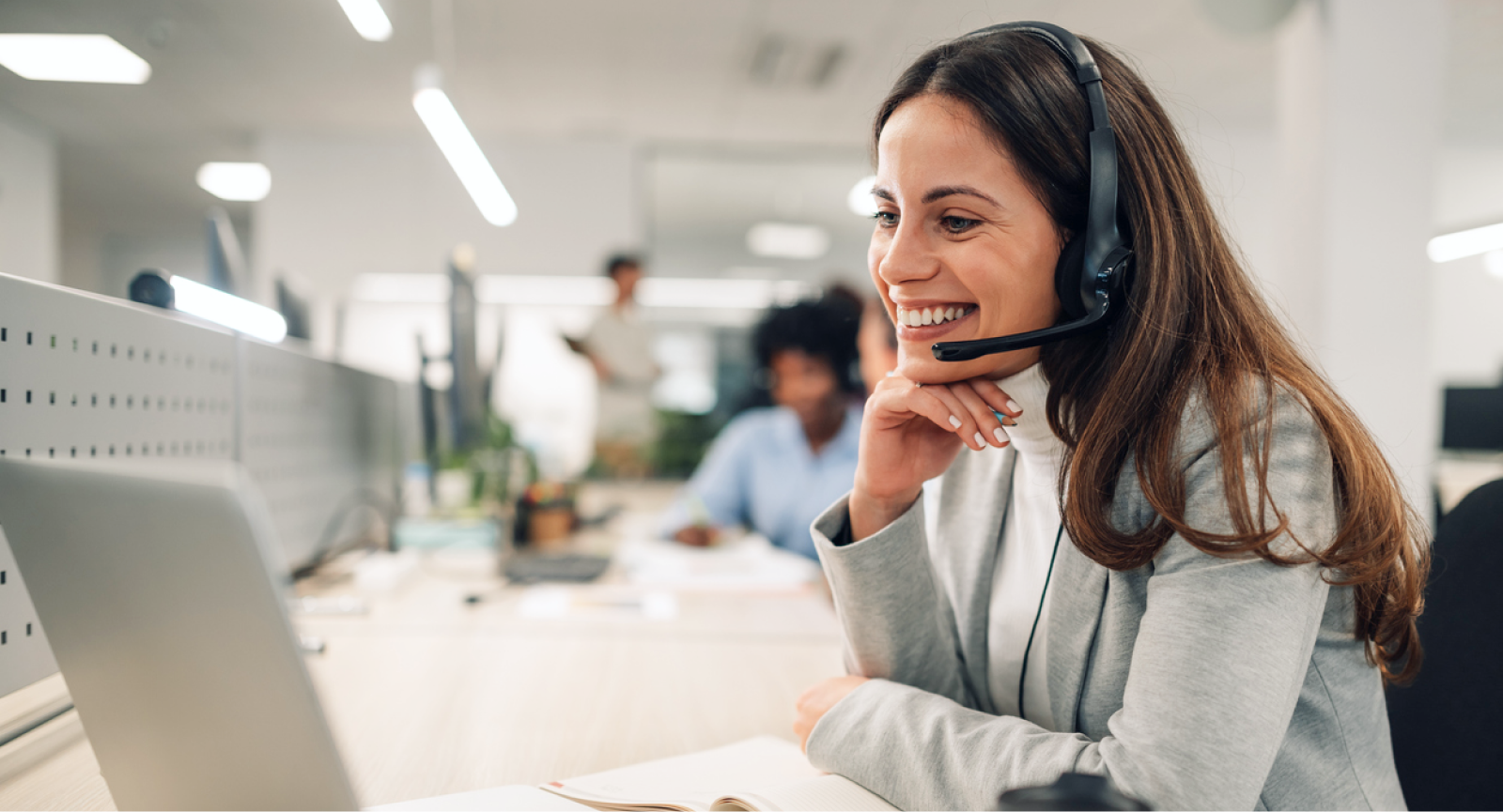 Employee smiling at laptop with headset on
