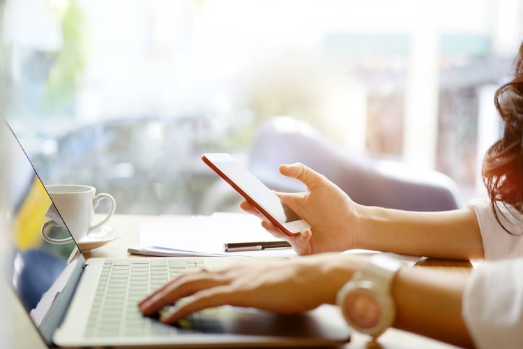 Woman using phone and laptop to activate Giftogram gift cards