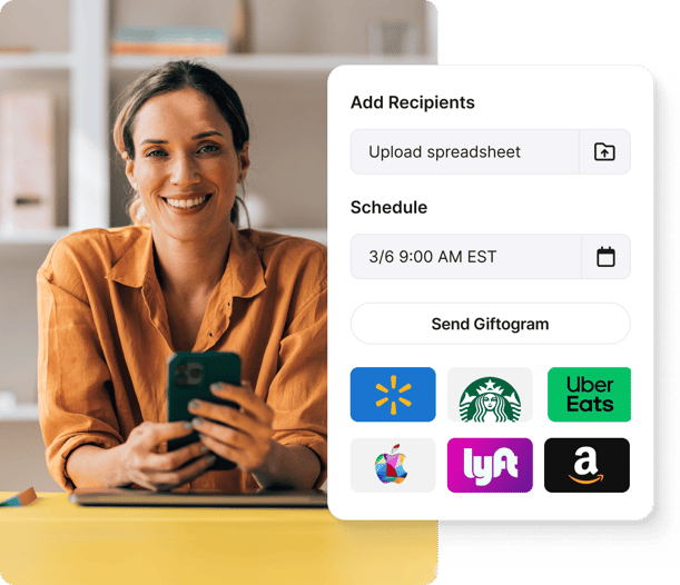 Smiling woman holds phone beside a Giftogram screen to upload recipients, schedule, and send gift cards for employee recognition.