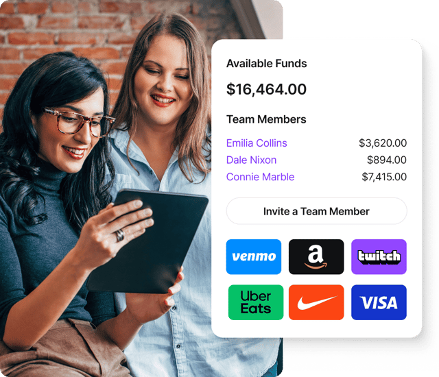 Two women happily viewing a Giftogram dashboard on a tablet, managing team member funds and gift card options for employee recognition.
