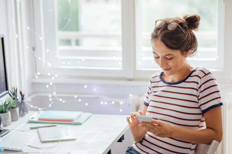 a woman at her desk decorated with string lights