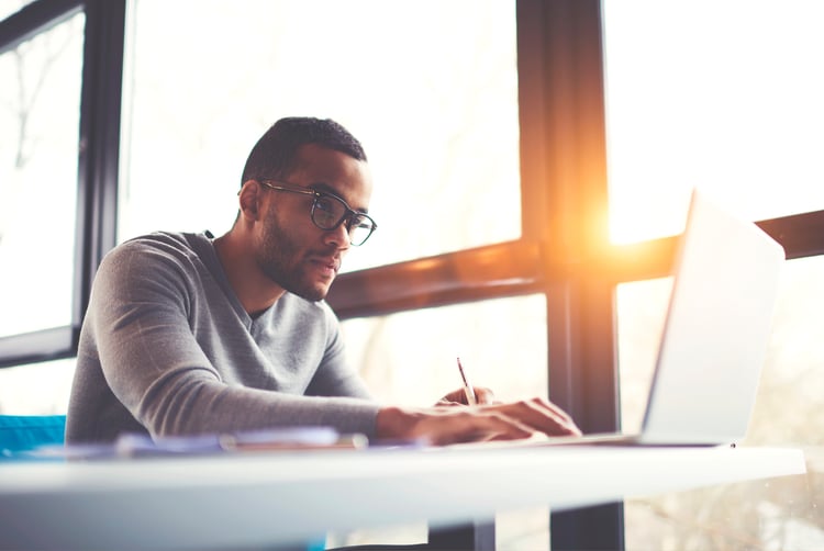 Millennial male employee enhancing his skill sets at a laptop 