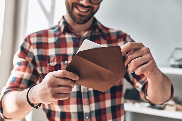 Employee smiling while opening envelope with volunteer program rewards inside