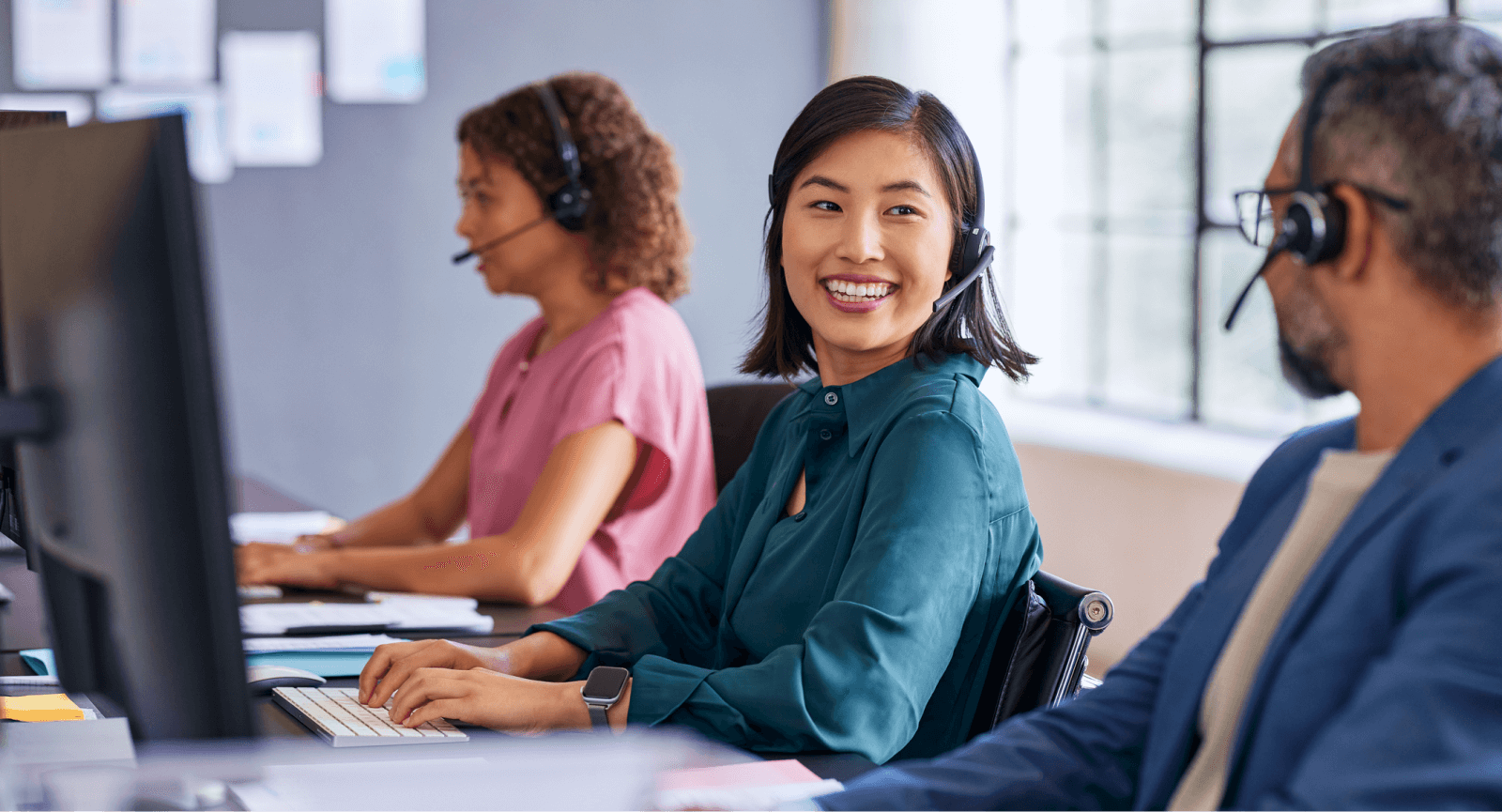 Smiling customer support agent with headset, alongside colleagues, ready to assist Giftogram clients.