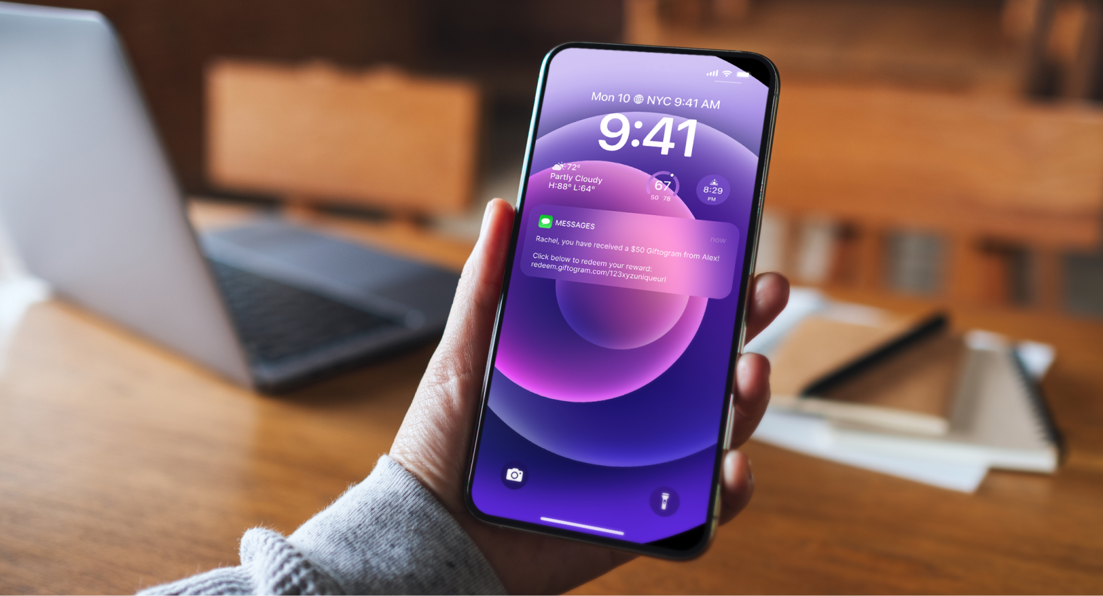 Hand holds smartphone showing a $50 Giftogram notification, rewarding an employee.