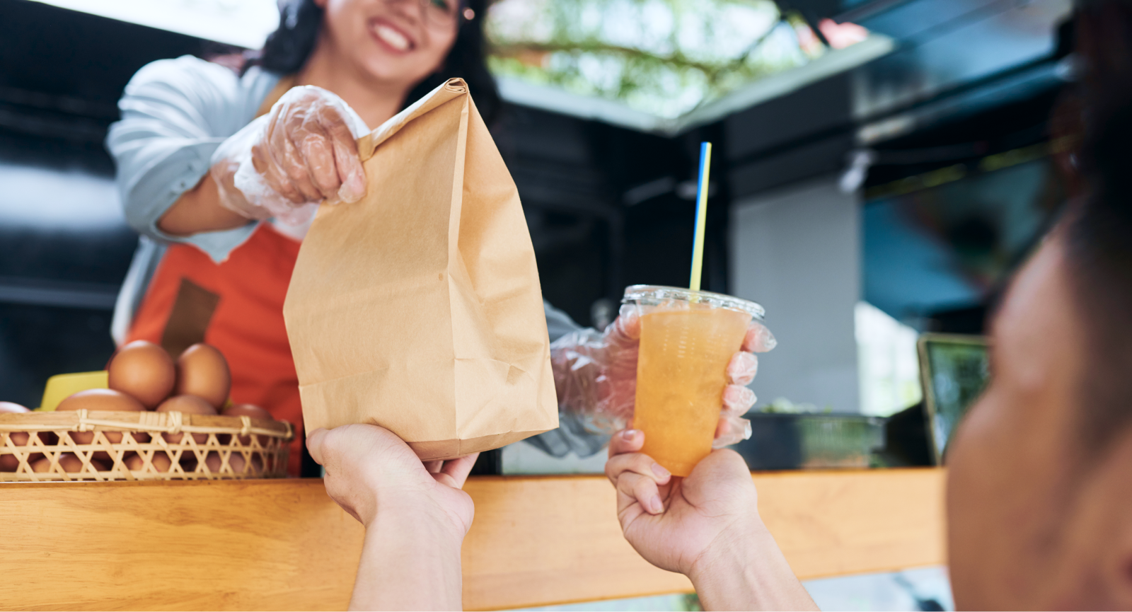 Happy vendor hands a customer a food bag and drink, representing the joy of receiving a gift or reward from a Giftogram.
