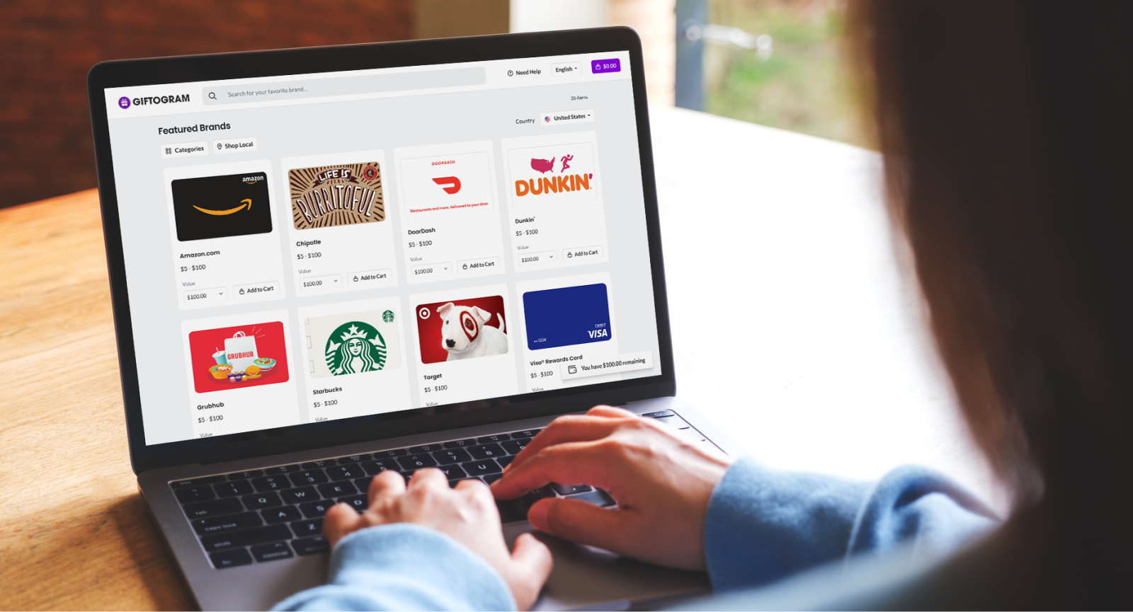 Person typing on a laptop displaying Giftogram's featured gift cards, selecting options to incentivize or appreciate recipients.