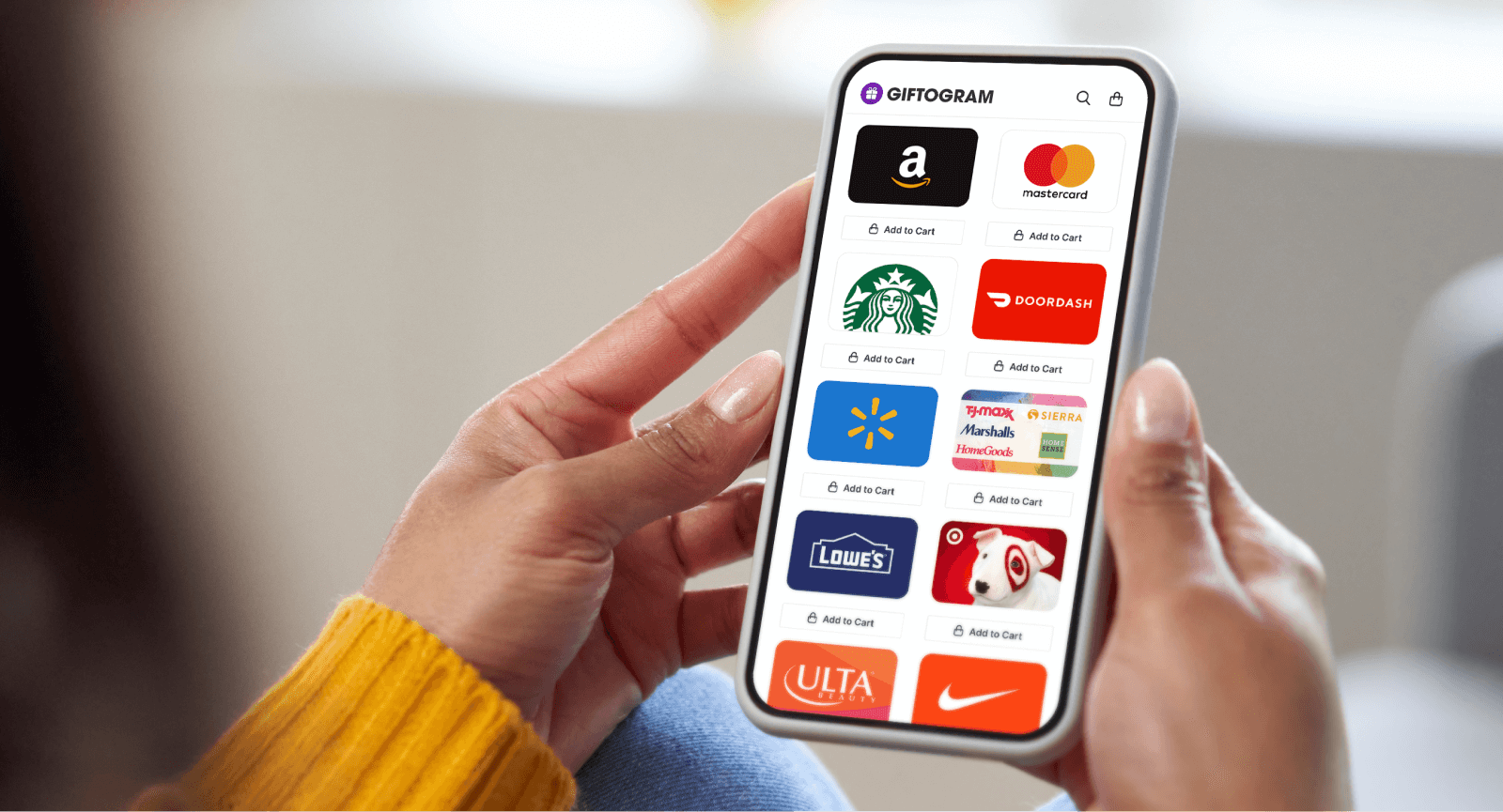Person holds a phone displaying the Giftogram platform with gift card logos like Amazon, Starbucks, and Target, for employee recognition.