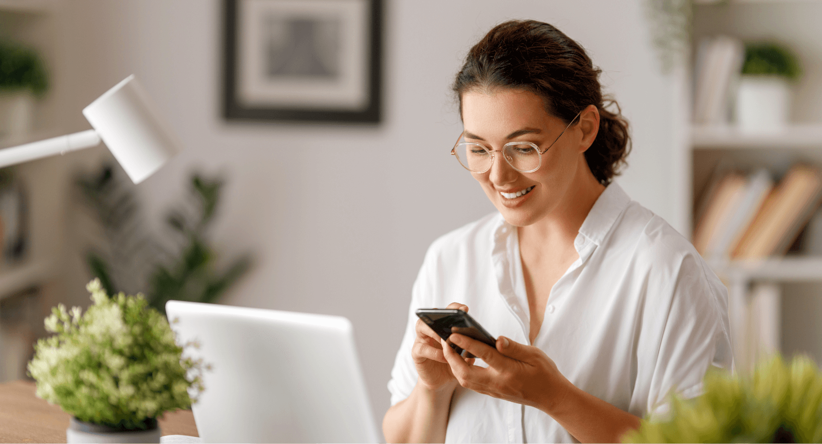 Smiling woman in glasses looks at her phone screen, appreciating a Giftogram recognition.