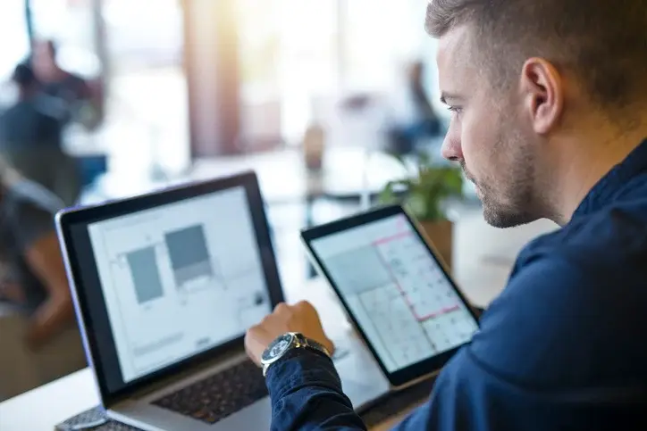 Man reviewing data on laptop and tablet, planning a Giftogram incentive program.