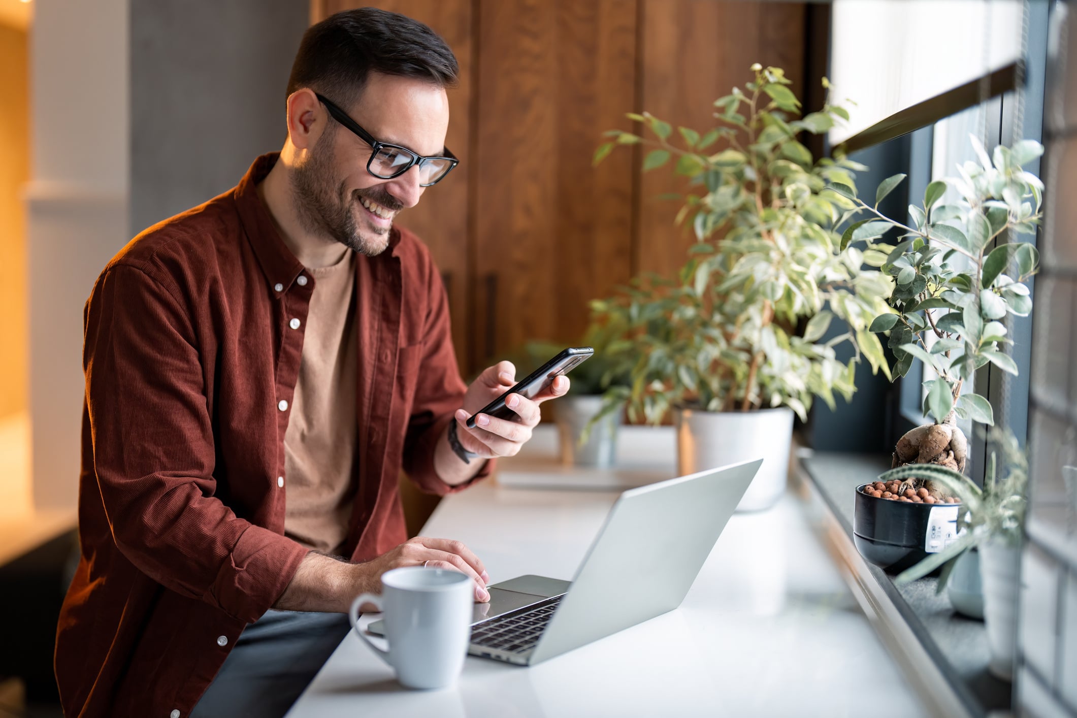 Happy man checking his phone while working, delighted by recognition or a reward.